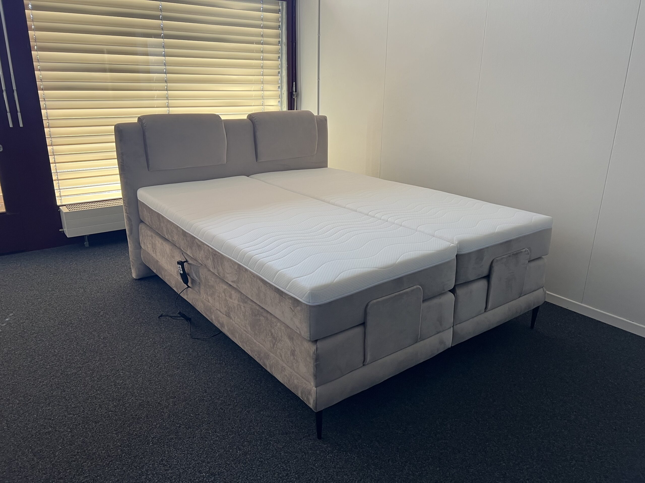 wave_riviera-16-vorne1 Elektrisch verstellbares Boxspringbett in Hellgrau mit gepolstertem Kopfteil, Vorderansicht.